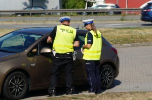 policjanci stoją przy samochodzie rozmawiają z kierowcą przez uchyloną szybę