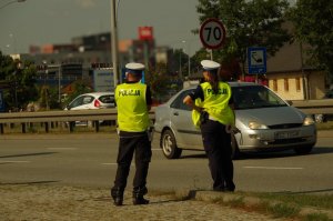 policjanci ruchu drogowego stoją przy drodze zatrzymują auta