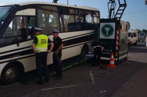 policjant wraz z funkcjonariuszem ITD rozmawiają z kierowcą autobusu przez uchyloną szybe w aucie