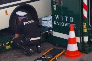 policjant przy autobusie ogląda koło tylne z bliska