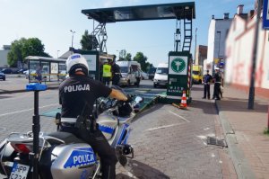 policjant siedzi na motocyklu, w tle mobilna stacja kontroli pojazdów ITD