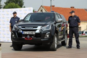 policjanci stoją po dwóch stronach nowego czarnego nieoznakowanego radiowozu terenowego ISUZU