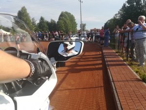 tor speedrowerowy, wokół ogrodzenia kibice, w lusterku motocykla widać policjanta na motocyklu