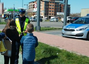 policjantka uśmiecha się do dzieci stojących przed nią