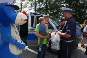 policjanci przekazują reklamówkę mężczyźnie z dzieckiem na ręku