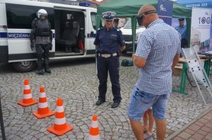 policjantka ruchu drogowego i mezczyzna który ma założone alkogogle i chodzi między pachołkami