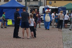 policjanci rozmawiają z jmieszkańcami podczas festynu w tle Sznupek