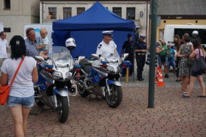 policjnat na motocyklu siedzi, obok przechodzą ludzie i przyglądają się motocyklom