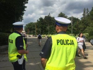 na pierwszym planie dwóch umundurowanych policjantów w kamizelkach odblaskowych, w tle pielgrzymi oraz Jasna Góra