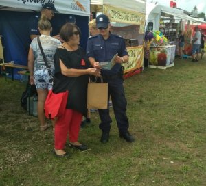 policjant wręczajacy ulotkę kobiecie