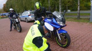 policjant, który kuca przy motocyklu i ogląda koła