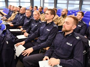 wyróżnieni policjanci, którzy siedzą w rzędach na auli