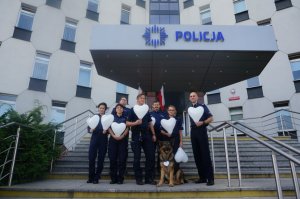 policjanci stoja na schodach przed komendą i trzymają w ręce białe balony w kształcie serca