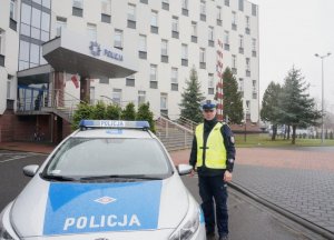 umundurowany policjant stojący przy radiowozie