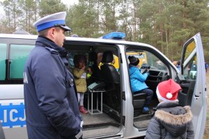 radiowóz w którym siedzą dzieci, obok