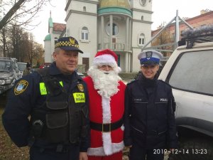 policjantka, strażnik miejski i Mikołaj, w tle wieże koscioła