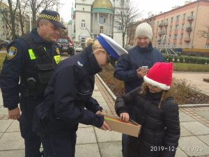 policjantka ze strażnikiem miejskim wręcza dzieciom odblaski