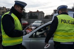 dwóch policjantów stoi przy samochodzie od strony kierowcy