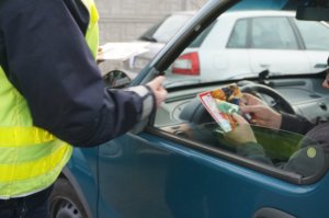 policjant wręcza kierowcy ulotkę