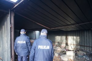 dwóch policjantów spradzają miejsce zabudowane blachą