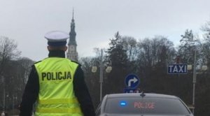 policjant drogówki stoi tyłem, w tle radiowóz nieoznakowany i Jasna Góra