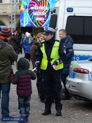 policjant przy radiowozie rozdaje ulotki matce z dzieckiem