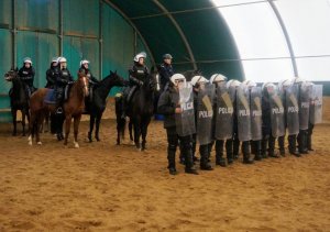 policjanci na koniach stoją za szykiem zwartym policjantów z SPPP