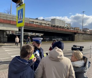 policjant przy przejściu dla pieszych razem z dwoma osobami