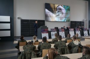 siedzący na krzesłach w auli Komendy Miejskiej Policji w Czestochowie uczniowie oglądają film na ekranie