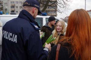 policjant w mundurze rozdaje Paniom tulipany