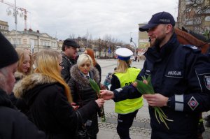 policjant w mundurze rozdaje Paniom tulipany