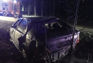 samochód stoi w przydrożnym rowie, na ulicy stoi policjant i strażak