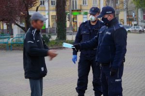 policjanci wręczają maseczkę mężczyźnie, który jej nie posiada