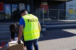 policjant w ubraniu cywilnym przekazuje za pokwitowaniem płyn wysokoprocentowy pracownikom służby medycznej