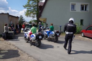 dzieci siedzą na motocyklach w tle grupa podopiecznych z domu dziecka