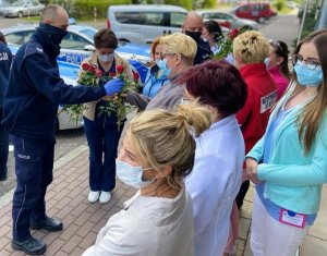 policjant wręcza kwiaty pielęgniarkom i położnym