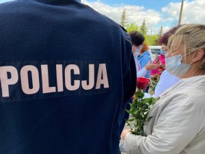 napis POLICJA na mundurze, w tle czerwone róże