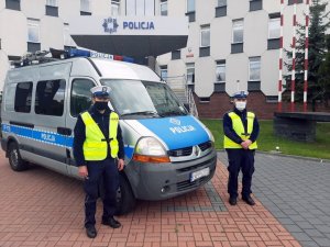 policjanci na tle głównego wejścia do Komendy Miejskiej Policji w Częstochowie stoją obok radiowozu