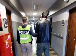 policjant prowadzi zatrzymanego po korytarzu