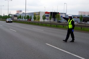 policjant zatrzymuje pojazd tarczą do zatrzymania