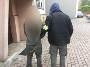 nieumundurowany policjant prowadzi zatrzymanego chwytem transportowym