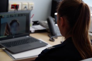 policjantka siedzi przy biurku, na biurku leży laptop