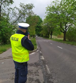 Policjant trzymający radar w ręku wycelowany w nadjeżdżający pojazd