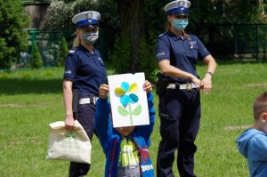 policjantki stoją na placu na zewnątrz przedszkola przed grupą dzieci, które recytują wiersz