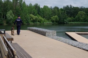 policjant z psem służbowym patroluje rejon kąpieliska wodnego