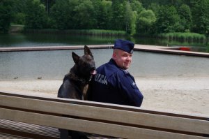 policjant z psem służbowym patroluje rejon kąpieliska wodnego