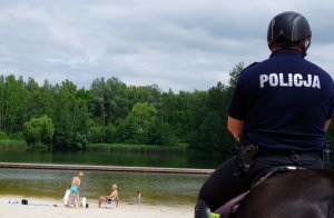 policjant na koniu patrzy na kąpielisko wodne