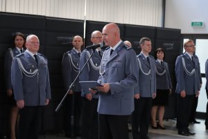 komendant przemawia przy mikrofonie w tle policjanci