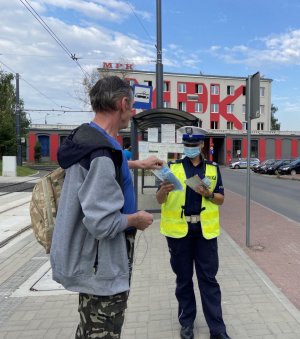 policjantka wręcza maseczkę pasażerowi