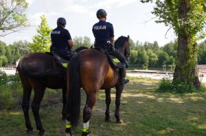 policja konna patroluje teren przy akwenie wodnym